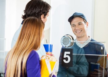 Couple Buys Movie Tickets at Box Office from Smiling Attendant