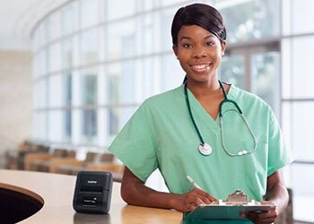 Nurse standing by desk beside mobile printer