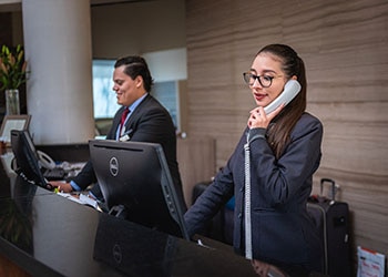 Hotel Front Desk Reception Staff Talk To Customers Over the Phone and in Person