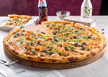 Pizza on table with silverware and soda