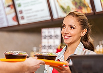 Woman handing food order to customer