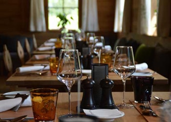 Restaurant Tables Lined Up with Plates, Silverware and Wine Glasses