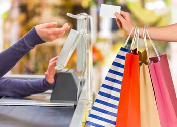 Retail Customer Holding Bags and Giving Cashier Credit Card